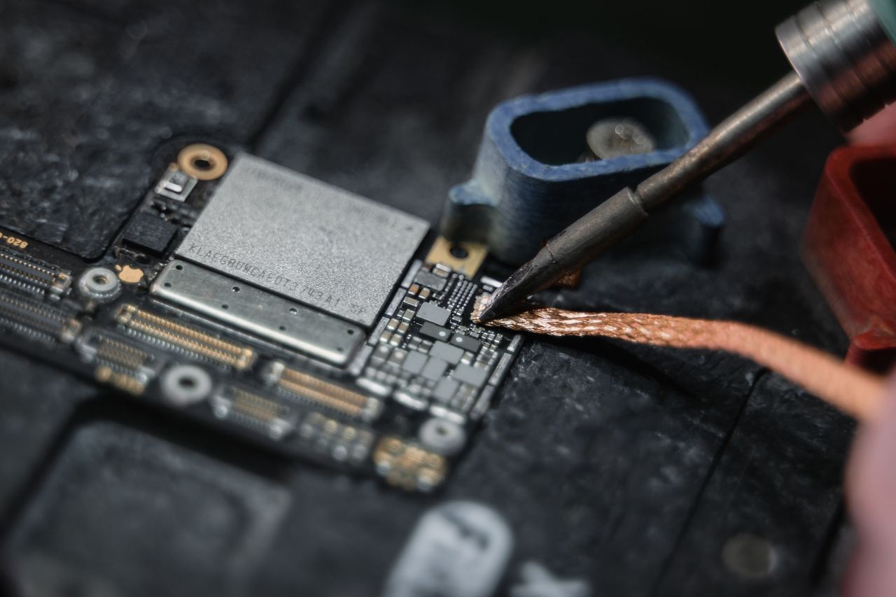 Contact Detailed close-up of a soldering iron working on a circuit board, showcasing electronics repair.